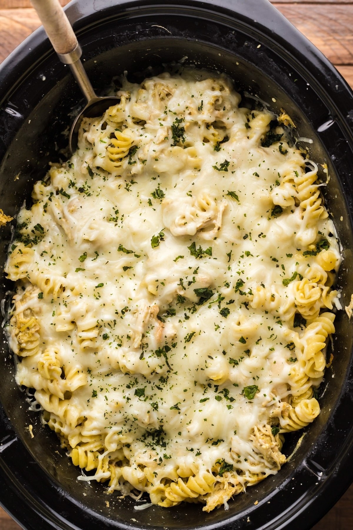 A slow cooker filled with cheesy pesto pasta.